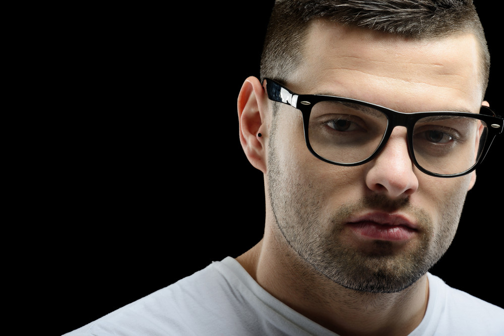 Smart looking guy with glasses in front of a black background