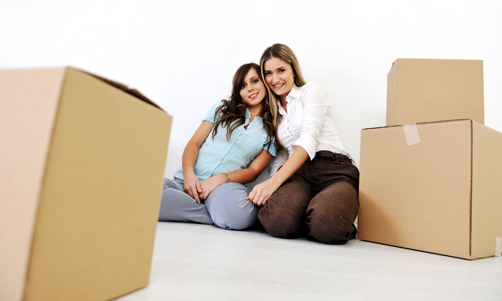 Two beautiful young woman in the room with boxes for moving