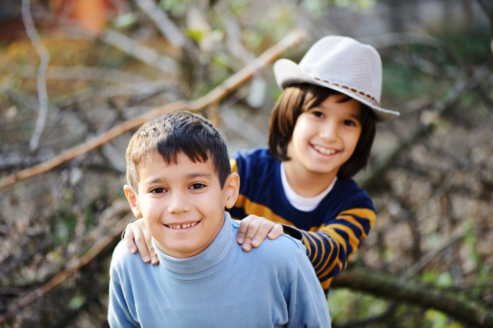Two children portrait on timber tree outdoor in nature