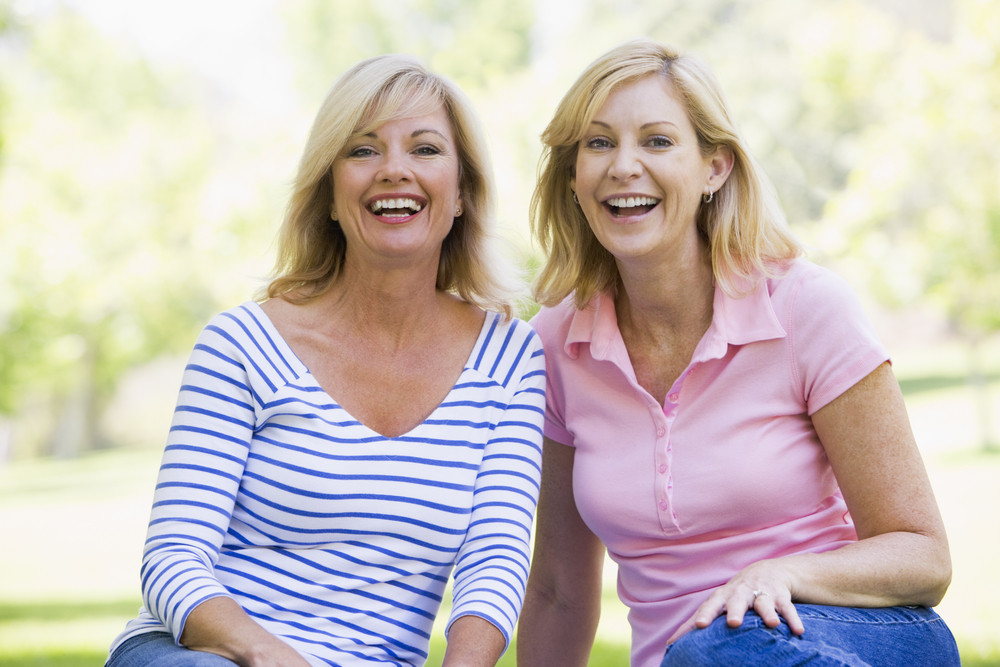 Two women sitting outdoors smiling Royalty-Free Stock Image - Storyblocks