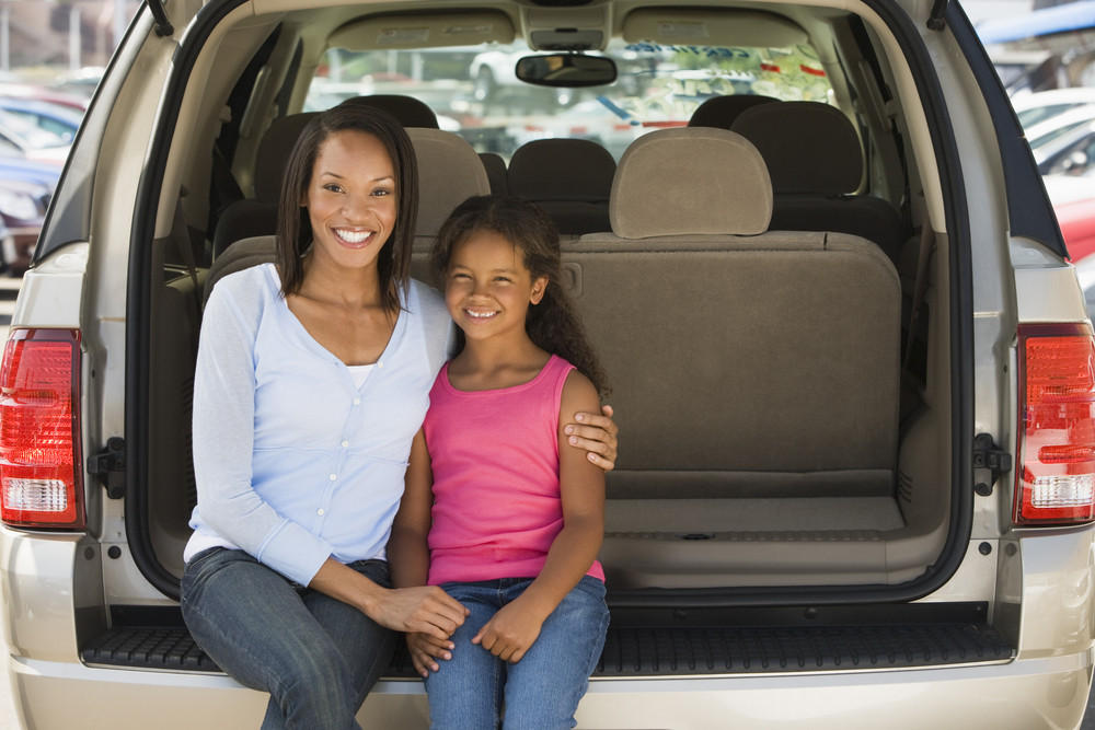 Woman with young girl sitting in back of van smiling Royalty-Free Stock ...