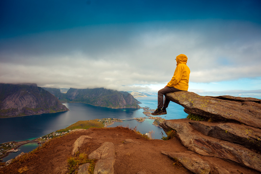 Male tourist sitting on the cliff. Beautiful mountain landscape of ...