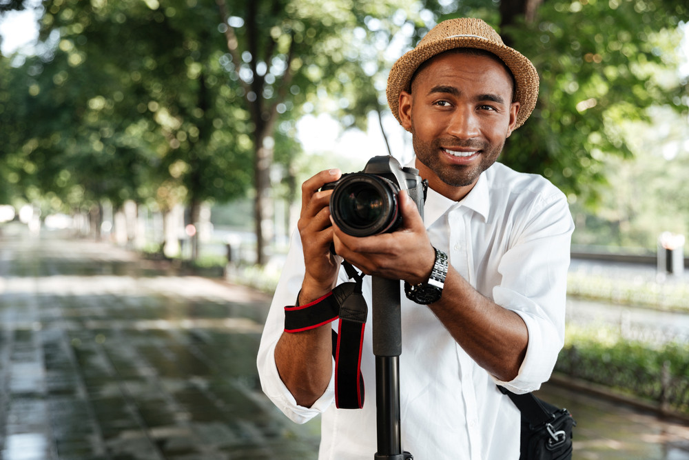 Funny black man in park with camera and hat