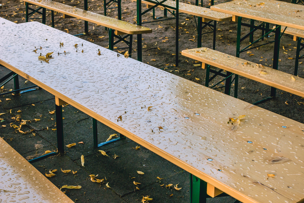 Empty beer garden in fall without guest due to rainy weather. Empty table and benches