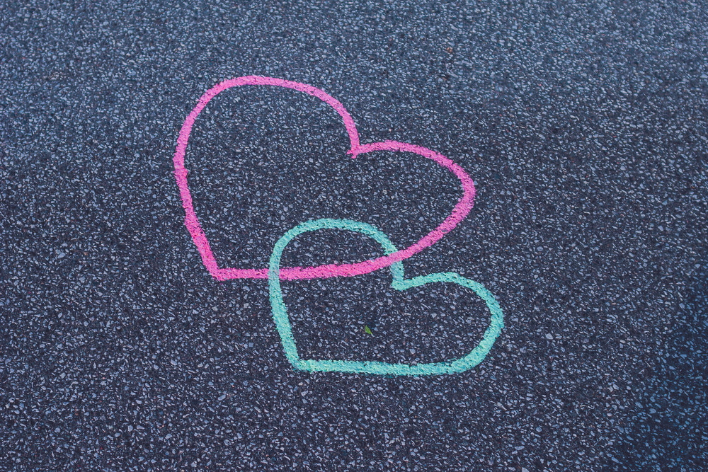 Two hearts drawing chalk on the asphalt