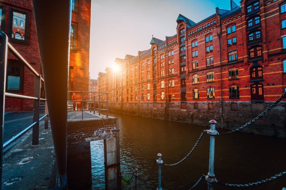 A red brick multi-storey houses of Speicherstadt Hamburg. Famous landmark of old red brick buildings in golden sunset light. Scenic evening view with canal handrail in foreground