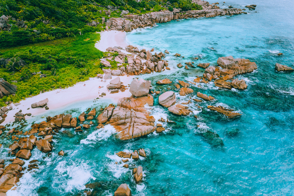 Aerial drone photo of group of rocks on tropical hidden secret beach Marron at La Digue island, Seychelles. White sand beach with turquoise ocean water and orange granite rocks