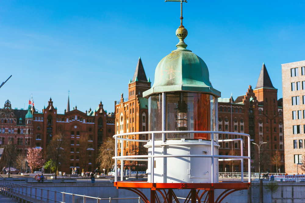 Close up of old beacon lighthouse and red brick building in background, Hafencity - Speicherstadt in Hamburg, Germany