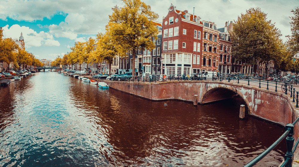 Romantic Amsterdam canals with bridges, boats and typical Dutch houses. Holland, Netherlands. Cityscape in terracotta colors