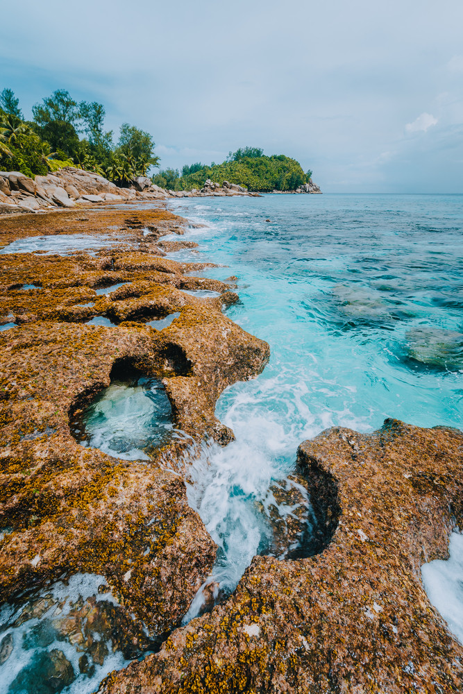 Rugged coastline of paradise beach with granite rocks and blue crystal clear water on a rough coast of Anse Bazarca, Seychelles