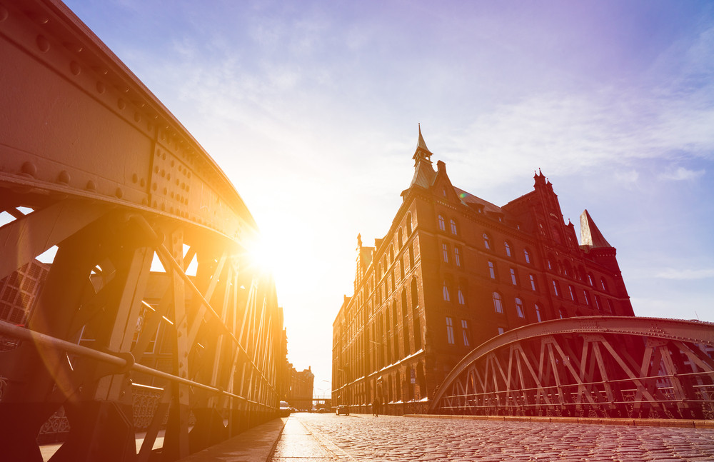 Silhouette of Bridge and Buildings in evening sun rays in low angle view. Speicherstadt Hamburg. Famous landmark of old buildings made with red bricks