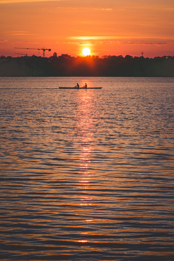 Silhouette of Team work oft two young men in a row boat at sunset