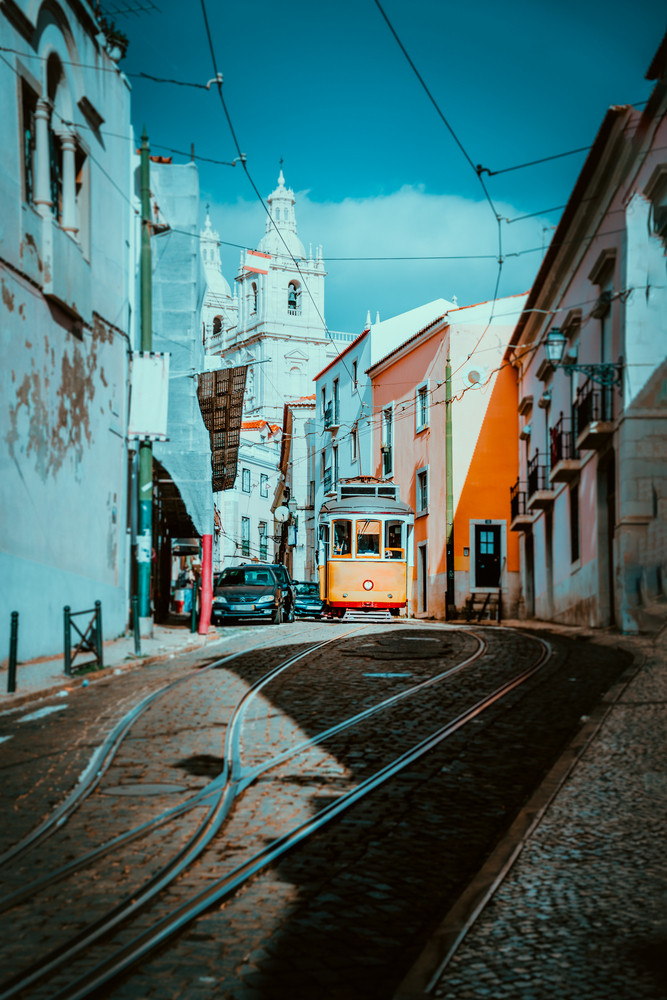 Summer cityscape of Lisboa. Red tram going down the hill along old traditional houses. sunny afternoon, narrow streets, cobblestones winding road, vacation in Lisbon
