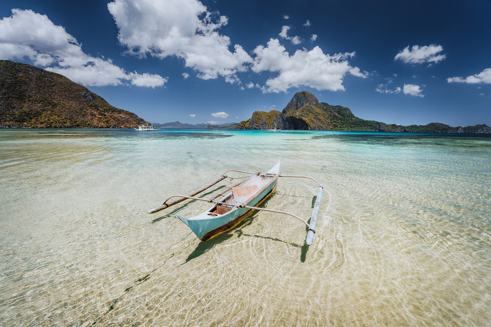 Traditional filippino fishermen banca boat in blue tropical lagoon at El Nido bay with Cadlao Island on Background. Palawan Island, Philippines