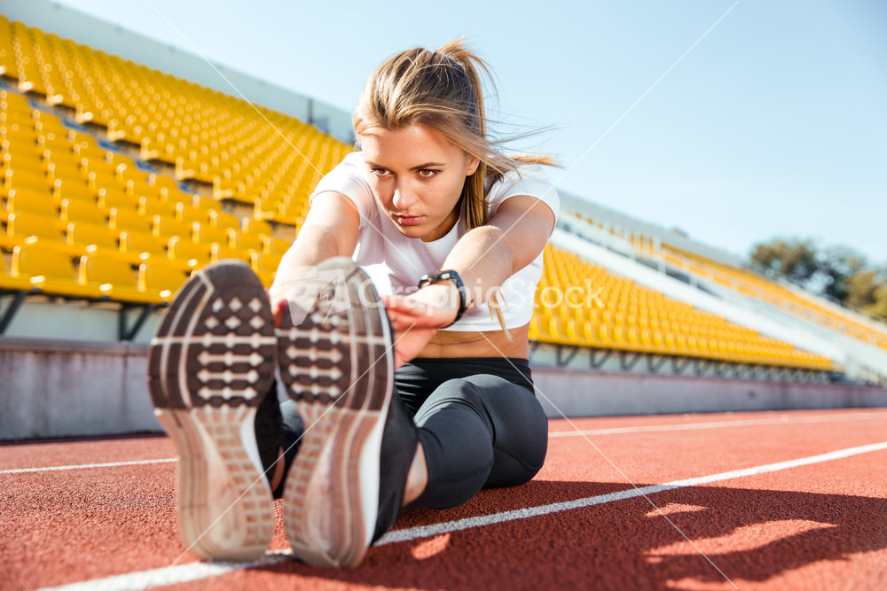 Woman stretching on the floor at stadium