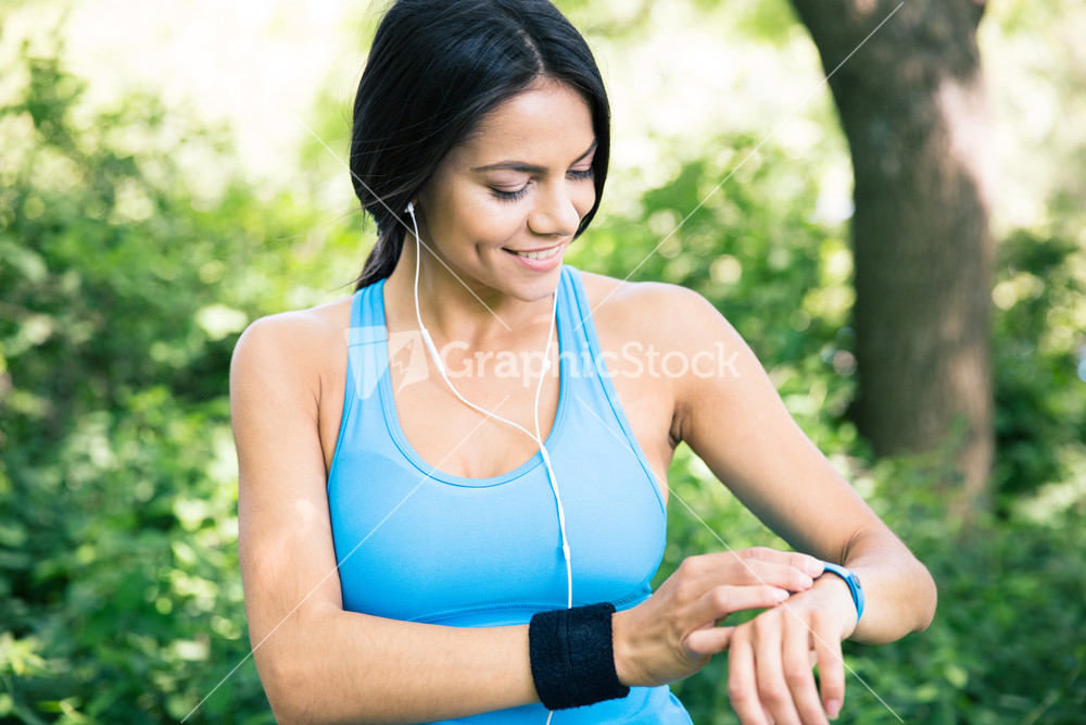 Smiling sporty woman using smart watch outdoors