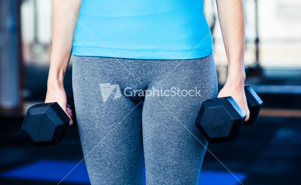 Closeup image of a woman standing with dumbbells
