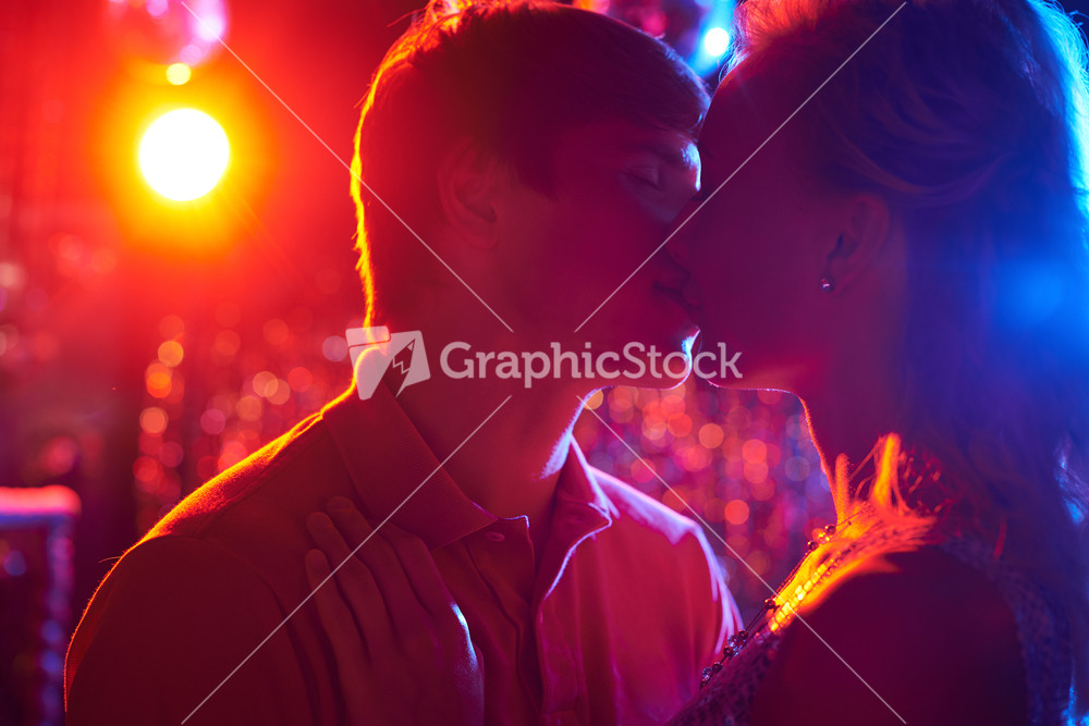 Amorous Couple Kissing While Dancing In The Night Club