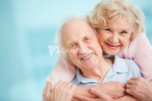 Happy And Affectionate Elderly Couple Looking At Camera With Smiles