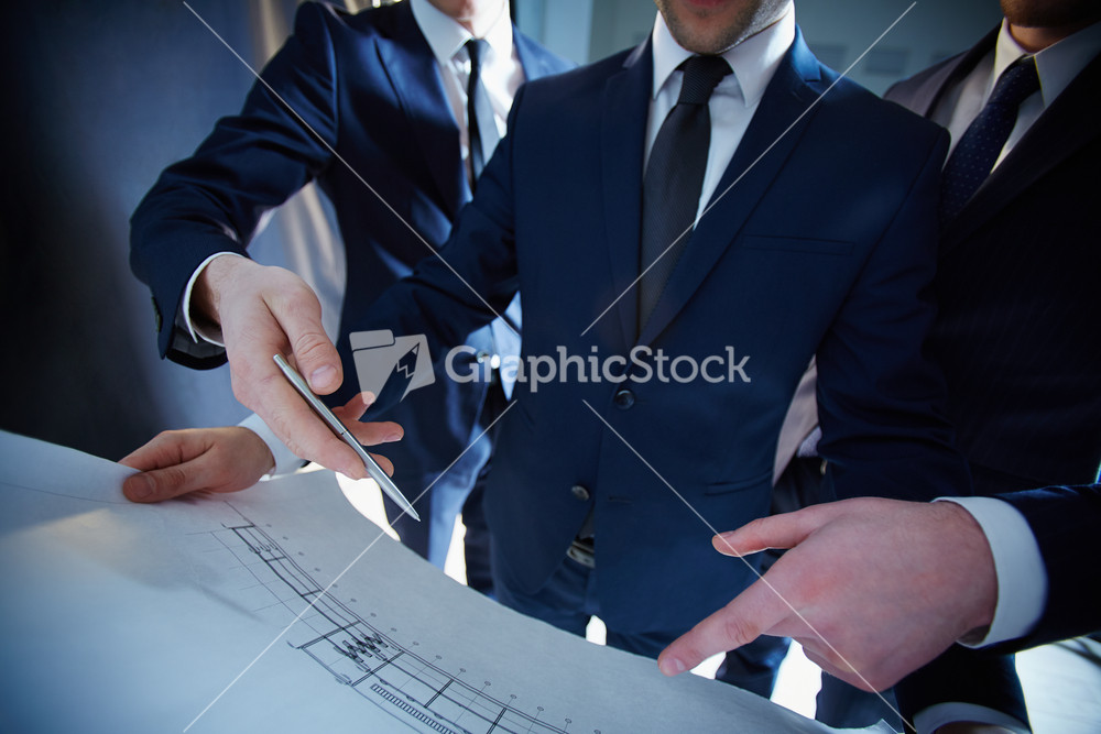 Cropped Image Of Professional Engineers Working With The Construction Blue Print On The Foreground