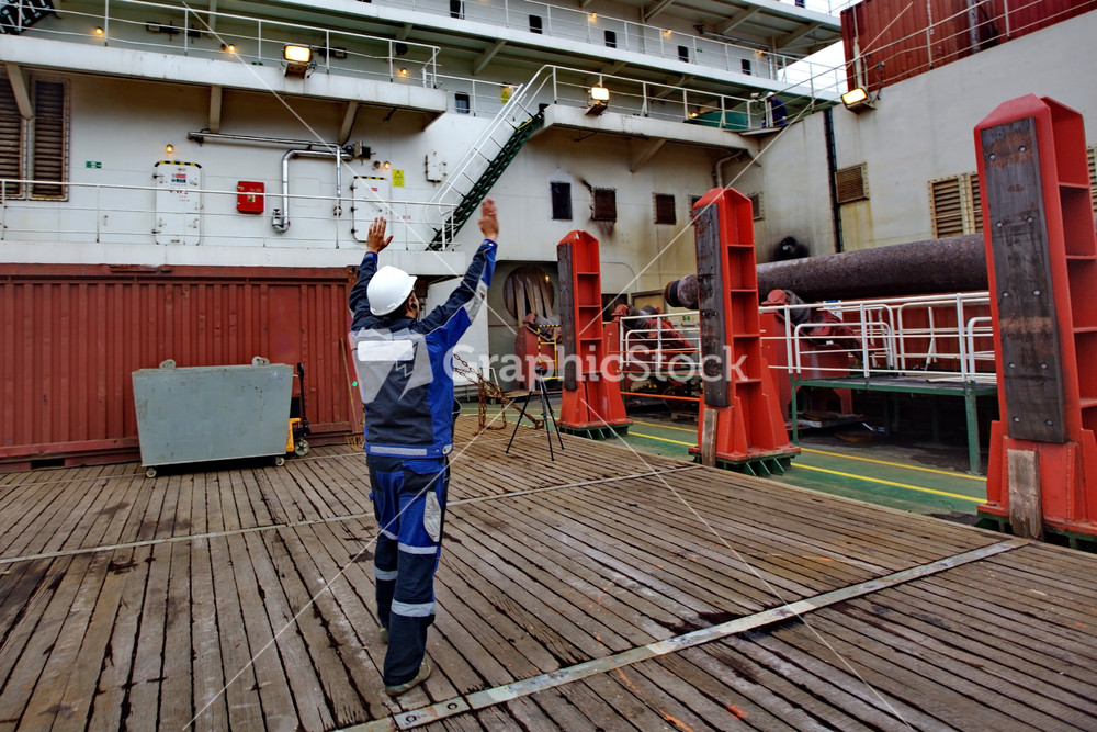 The worker shows where to put freight. deck of the pipelaying vessel.