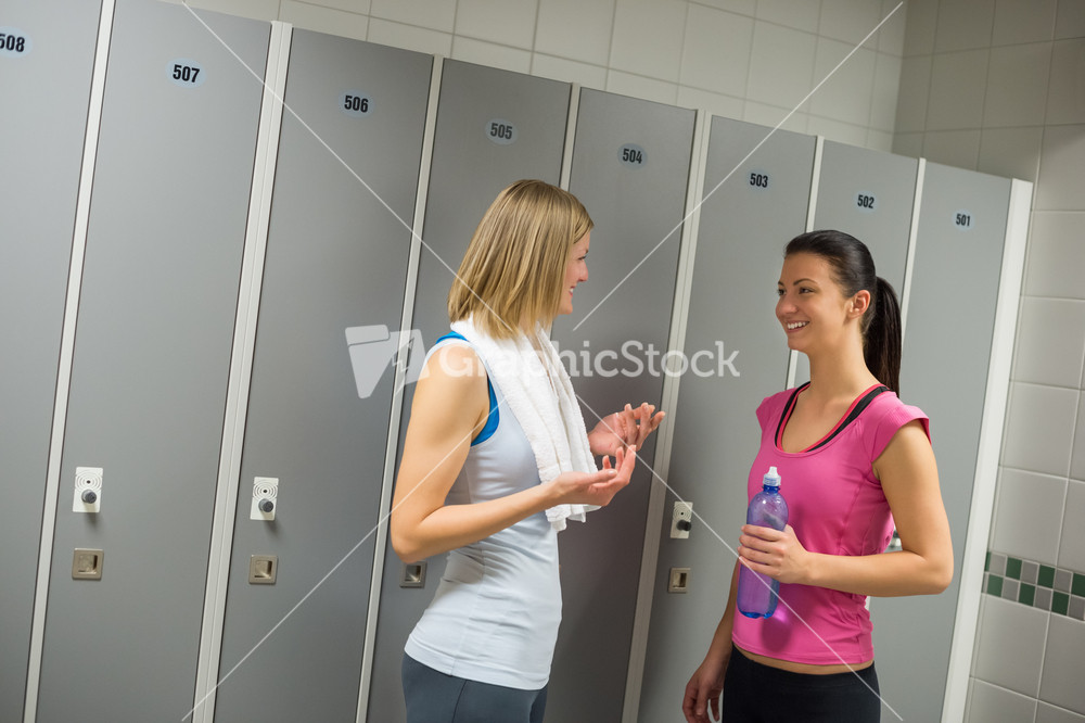 Happy fit women talking in locker room at gym