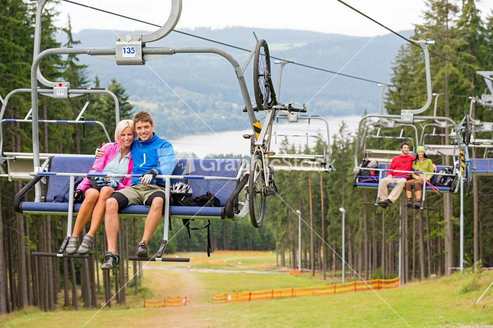 Smiling couples using chair lift in scenic landscape