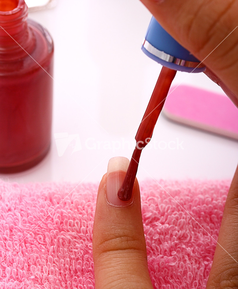 Woman Applying Red Nail Polish To Her Nails